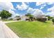 Landscaped yard with a tan house and two-car garage visible at 17606 Se 93Rd Butler Ct, The Villages, FL 32162
