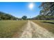 Dirt driveway leading to a home with open green fields on either side at 4248 Ne 175Th Street Rd, Citra, FL 32113