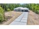 Long concrete driveway approaches the modern exterior with a metal roof and attached garage doors at 6877 Sw 131St Cir, Ocala, FL 34481