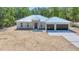 Modern home with metal roof, wood front door and two-car garage, set amidst a natural landscape at 6877 Sw 131St Cir, Ocala, FL 34481