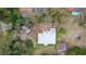 An aerial view of a home featuring a light-colored roof, sheds, and surrounding trees at 70 Se 81St Pl, Ocala, FL 34480