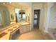 Bathroom vanity with marble countertop and mirror, leading into bathroom with soaking tub at 9340 Sw 9Th Ter, Ocala, FL 34476