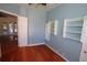 Bedroom with blue walls, hardwood floors, ceiling fan, built-in shelving, and a doorway at 9340 Sw 9Th Ter, Ocala, FL 34476