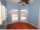 Bedroom featuring hardwood flooring, blue walls, built-in shelves, ceiling fan, and two corner windows at 9340 Sw 9Th Ter, Ocala, FL 34476
