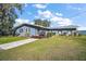 Newly renovated waterfront home with a gray exterior, landscaping, and a spacious yard at 10455 Se 143Rd St, Summerfield, FL 34491