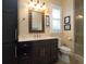 Bathroom with dark vanity, toilet, shower, and decorative mirror at 11130 W Highway 326, Ocala, FL 34482