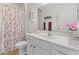 Clean bathroom, featuring a shower/tub, white vanity, and floral shower curtain at 17385 Se 110Th Ter, Summerfield, FL 34491