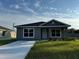 Gray house with a white door, landscaping, and a paved driveway at 6574 Se 108Th Ln, Belleview, FL 34420