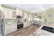 Well-lit kitchen featuring white cabinets, stainless steel appliances, granite countertops, and a breakfast table by the window at 1065 Ne 31St Ter, Ocala, FL 34470