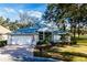 Single-story home with a white garage door and a brick driveway, surrounded by lush landscaping at 10801 Sw 71St Ave, Ocala, FL 34476