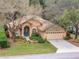 Tan house with teal front door, two-car garage, and landscaped yard at 19586 Sw 84Th Pl, Dunnellon, FL 34432