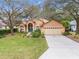 Tan house with teal front door, two-car garage, and landscaped yard at 19586 Sw 84Th Pl, Dunnellon, FL 34432