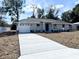 Newly constructed one-story home with gray exterior, white garage door, and landscaping at 4310 Se 139Th Pl, Summerfield, FL 34491