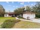 Single-story home with white exterior, brown roof, and lush landscaping at 9185 Sw 197Th Cir, Dunnellon, FL 34432