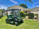 A well-maintained golf cart sits parked in front of a home with lush landscaping and a vibrant green lawn at 9581 Se 168Th Elderberry Pl, The Villages, FL 32162