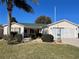 Cute one-story house with a green roof, two-car garage, and manicured lawn at 9581 Se 168Th Elderberry Pl, The Villages, FL 32162