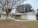 Tan single-story house with attached garage and landscaped lawn at 10729 Sw 62Nd Ave, Ocala, FL 34476