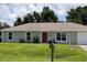 Ranch-style home with gray siding, red door, and a well-maintained lawn at 13410 Sw 3Rd Ct, Ocala, FL 34473