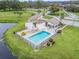 Aerial view of community pool, clubhouse, and surrounding landscape at 21202 Sandalwood Dr # 21-202, Wildwood, FL 34785