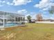 View of fenced backyard featuring a screened-in pool, surrounded by lush greenery at 4880 Sw 106Th St, Ocala, FL 34476