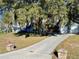 Long driveway leading to a charming home and detached garage under a canopy of trees at 6701 Se 99Th Pl, Belleview, FL 34420