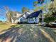 Exterior elevation of home with manicured lawn, mature trees, large driveway, and detached garage with two bays at 6701 Se 99Th Pl, Belleview, FL 34420
