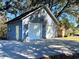 Exterior of a two-car garage featuring blue siding, white doors, and stone accents at 6701 Se 99Th Pl, Belleview, FL 34420
