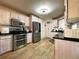 Well-lit kitchen featuring stainless steel appliances, black countertops, and wood-look flooring at 6701 Se 99Th Pl, Belleview, FL 34420