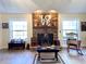 Inviting living room featuring a stone fireplace and rustic decor, complemented by natural light from adjacent windows at 6701 Se 99Th Pl, Belleview, FL 34420