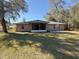 Back of house with screened porch and grassy yard at 73 Fir Dr, Ocala, FL 34472