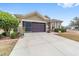 Tan house with brown doors, landscaping, and a two-car garage at 7358 Sw 101St Ave, Ocala, FL 34481