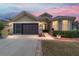 Tan house with brown doors, landscaping, and a two-car garage at 7358 Sw 101St Ave, Ocala, FL 34481