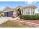 Tan house with brown doors, landscaping, and a two-car garage at 7358 Sw 101St Ave, Ocala, FL 34481