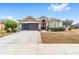 Tan house with brown doors, landscaping, and a two-car garage at 7358 Sw 101St Ave, Ocala, FL 34481
