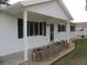 Front view of a white house with a covered entryway and brick planter at 11500 Sw 136Th Pl, Dunnellon, FL 34432