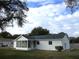 White house with a screened porch and a well-maintained lawn at 11500 Sw 136Th Pl, Dunnellon, FL 34432