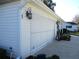 Attached one-car garage features a metal roll-up door on a house with white siding and green landscaping at 13779 Sw 111Th Ave, Dunnellon, FL 34432