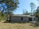 Backyard view of the single-story home with large trees in the background at 14268 Se 27Th Ct, Summerfield, FL 34491