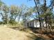 Backyard view showcasing a single-story home with large trees and a spacious lawn at 14268 Se 27Th Ct, Summerfield, FL 34491