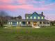 Two-story home exterior with wrap-around porch at dusk at 20921 Sw 36Th St, Dunnellon, FL 34431