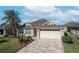 Well-maintained house featuring a paver driveway and lush landscaping at 2304 Grenadier Way, The Villages, FL 32162