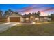 Tan house with brown roof, stone accents, and a wooden garage door at sunset at 4933 Sw 109Th Loop, Ocala, FL 34476