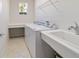 A well lit laundry room features tile floor, washer and dryer, utility sink, and shelving at 9836 Sw 75Th Street Rd, Ocala, FL 34481