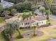 Aerial view of a yellow house with palm trees and a well-manicured lawn at 1244 Se 11Th St, Ocala, FL 34471