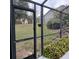 A view of the backyard through the screen showcasing lush plants and plenty of room to relax and enjoy the weather at 19950 Ibis Ct, Dunnellon, FL 34432