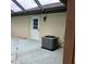 A view of the backyard patio with an air conditioning unit and exterior door at 19950 Ibis Ct, Dunnellon, FL 34432