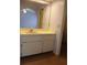 Bathroom vanity with white cabinets and sink, reflecting the bedroom in the mirror at 19950 Ibis Ct, Dunnellon, FL 34432