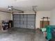 An inside view of a spacious two car garage with gray door and overhead storage at 19950 Ibis Ct, Dunnellon, FL 34432