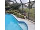 Screened in pool with blue tile and landscaped retaining wall at 19950 Ibis Ct, Dunnellon, FL 34432