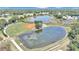 Aerial view of community with pond, baseball field, and lush green landscape at 3923 Manor Oaks Ct, Leesburg, FL 34748